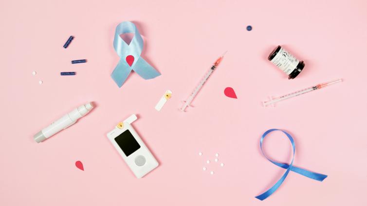 Photo of diabetes care items and ribbons, including glucose meter, testing strips, and shots. 